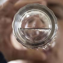 Verunreinigtes Trinkwasser belastet Gemeinden immer mehr Mann trinkt Wasser, Blick von unten durchs Wasserglas - Für Schweizer Gemeinden wird die Trinkwasseraufbereitung zum Problem. Sie fordern finanzielle Unterstützung vom Bund, doch dieser hat andere Pläne