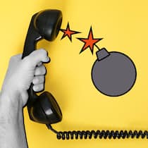 Hier spricht nicht die Polizei! Eine Hand hält einen Telefonhörer, aus dem eine Bombe springt. Telefonbetrüger rufen oftmals als falsche Polizisten an und setzen ihre Opfer unter Druck, mit dem Ziel Geld oder sensible Daten zu stehlen. Das können Sie tun, wenn Sie jemand versucht reinzulegen.