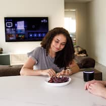 Die Spione in Ihrem Wohnzimmer – smarte Lautsprecher und TV Paar an Wohnzimmertisch, im Hintergrund ein TV - Ob Internet-Router, Kamera oder smarte Lautsprecher: Geräte, die ans Internet angeschlossen sind, können Teil von internationalen Spionagenetzwerken werden. Der Beobachter zeigt, wie Sie sich schützen