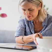 8 praktische Apps für den Alltag Eine Frau schaut auf ihr Tablet während dem Kochen.