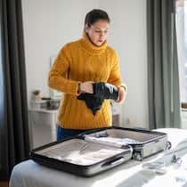 Zwei Wohnorte sind oft billiger Eine junge Frau packt ihren Koffer.