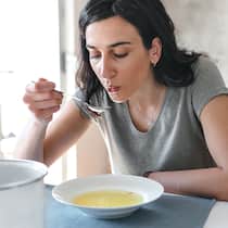 Das sollten Sie essen, um schneller gesund zu werden Eine Frau mit Grippe isst eine Suppe. Bei Erkältung und Grippe hilft es, die Ernährung ein wenig anzupassen.