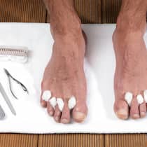 Wie man die Füsse pflegen sollte Ein Mann hat Nagelschere und Feile bereitgelegt, um die Füsse zu pflegen.