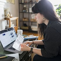 Hat das Reisebüro zu wenig informiert? Eine junge Frau schaut sich auf dem Laptop eine Buchungsseite an, um einen Flug zu buchen.
