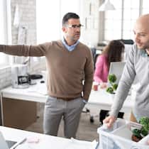 Was gilt bei Freistellung? Ein Chef bedeutet seinem Mitarbeiter, das Büro zu verlassen.