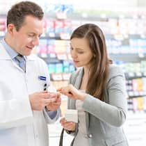 Weshalb muss ich in der Apotheke einen Zuschlag zahlen? Apotheker klärt Kundin über ein Medikament auf