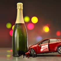 Wie viel Promille liegen drin? Symbolisches Bild in welchem ein Spielzeugauto in eine Sektflasche kracht