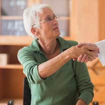 So überprüfen Sie, ob Ihr Arzt ohne Bewilligung arbeitet Patientin schaut Arzt an und gibt ihm die Hand