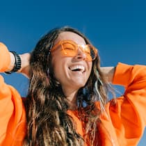 Die Sonne kann Ihr Leben verlängern Lachende Frau geniesst die Sonne - Sonnenstrahlung ist gefährlich, aber auch gesund. Die Wissenschaft hat neue positive Effekte entdeckt. Hautärztinnen denken um. Wie man die Sonne dosiert, ohne das Hautkrebsrisiko zu vernachlässigen