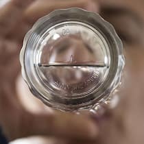 Chemikalien im Trinkwasser setzen Gemeinden unter Druck Mann trinkt Wasser, Blick von unten durchs Wasserglas - Für Schweizer Gemeinden wird die Trinkwasseraufbereitung zum Problem. Sie fordern finanzielle Unterstützung vom Bund, doch dieser hat andere Pläne