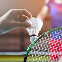 Antitherapie als Therapie – wenn Sport mehr bringt als Reden Men single badminton player holds racket and white cream shuttlecock in front of the net before serving it to another side of the court, soft and selective focus.2213567439