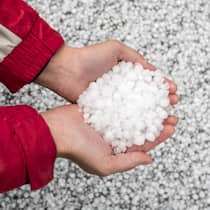 Wann die Versicherung für Hagelschäden zahlt Eine Person hat Hagelkörner in der Hand - Unwetter mit Hagel führen oft zu Schäden an Autos, Gebäuden und Möbeln. Welche Versicherung springt ein, wenn etwas beschädigt wurde