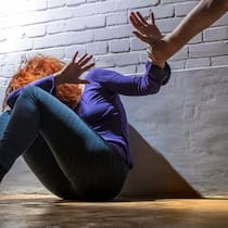 «Man kann sie nicht präventiv wegsperren» Eine Frau sitzt auf dem Fussboden und hält schützend ihre Hand vors Gesicht während eine andere Hand sie zu schlagen versucht.