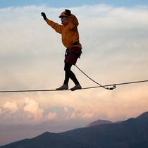 Wie riskant ist das Leben? Ein Mann geht über eine sogenannte Highline, ein Band, das zum Beispiel zwischen zwei Berggipfeln gespannt wird.
