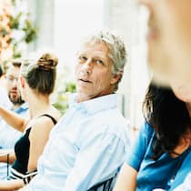 Wie wieder ins Gespräch kommen? Mann an Fest blickt nachdenklich zu anderem Mann