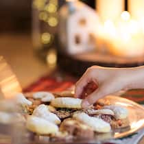 Geniessen ohne Reue Eine Frau nimmt einen Vanillekipfel von einer Platte mit Guetzli.