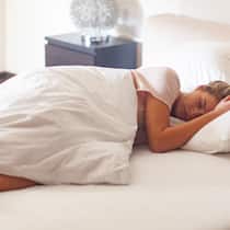 Die unsichtbaren Feinde des Schlafs Eine junge Frau liegt im Bett und schläft.