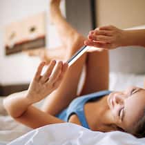 Knipsen, schicken, bereuen – wann sind Nacktbilder strafbar? Jugendliche liegt mit dem Smartphone auf dem Bett