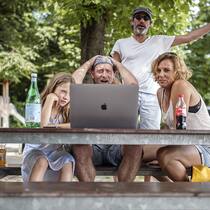 Kann ich den Zeitabstand beeinflussen? Freunde schauen sich im Park auf einem Notebook ein Fussballspiel zusammen an.