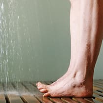 Die Kraft des kalten Wassers Füsse mit gespreizten Zehen unter der Dusche