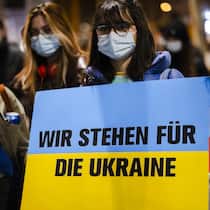 Das gilt in der Schweiz Junge Demonstrierende halten ein Plakat in den Farben der ukrainischen Flagge, auf der geschrieben steht «Wir stehen für die Ukraine».