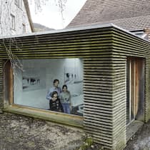 Denkmalschutz muss kein Hindernis sein Architekt Christoph Ecker mit seiner Familie im selbst umgebauten Haus in Oltingen. Blick von aussen durchs Fenster in den Anbau.