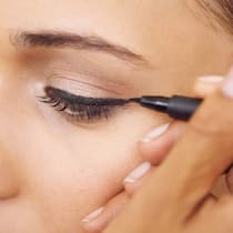 Präziser Strich für wenig Geld Closeup of a young woman getting eyeliner applied to her eyes