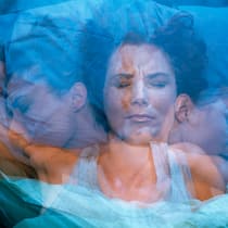 Was tun, wenn negative Gedanken den Schlaf rauben? Eine Frau wälzt sich nachts im Bett hin und her.