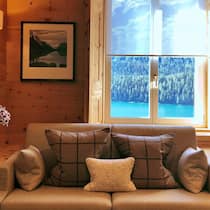 Der teure Traum vom Ferienhaus Eine schön eingerichtete Stube einer Ferienwohnung mit Blick auf einen See und Wälder.