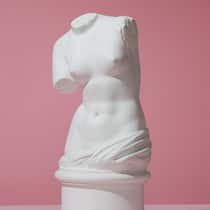 Unterstützung für den Beckenboden Ein Torso aus Gips der griechischen Göttin der Liebe und Schönheit, Venus, auf rosarotem Hintergrund.