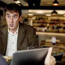 Wann lohnt sich eine Risiko-Lebensversicherung? Zwei Männer sitzen in einem Restaurant, einer zeigt dem anderen etwas auf einem Laptop
