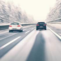 Das Fahrtempo den Umständen anpassen Zwei Autos fahren auf Autobahn im Winter