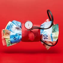 Dieses Mittel hilft nicht Bild zum Thema Gesundheitskosten.Ein Blutdruckmessgeraet zerquetscht Schweizer Banknoten der 9. Banknotenserie. Fotografiert am Freitag, 29.09.23 im Studio in ZürichFoto: Yves Roth