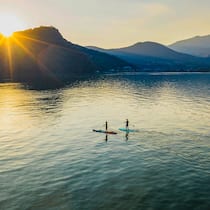 Fit bleiben mit kühlem Kopf Zwei Stand-Up-Paddler:innen auf dem Luganersee – kurz vor Sonnenuntergang