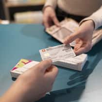 Wie einzelne Kantone jetzt die Prämienzahler entlasten wollen Frau gibt einer anderen Frau die Krankenkassenkarte - Wer profitiert von höheren Steuerabzügen für Krankenkassenprämien? Der Mittelstand oder Gutverdienende? In mehreren Kantonen laufen Initiativen. Ein Überblick