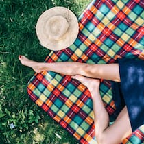 So kommen auch Bewegungsmuffel auf Trab Farbige Picknick-Decke auf einer Wiese mit nackten Beinen einer Person. Bewegungsmuffel stehen schnell unter Verdacht: zu bequem, zu undiszipliniert, zu wenig Willenskraft. Dabei tut ihr Körper genau das, wofür er gemacht ist: Energie sparen. Wie man sich trotzdem mehr bewegt.