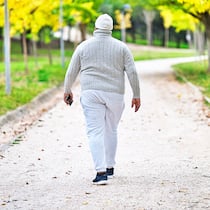 «Ich schäme mich für mein Gewicht» Ein übergewichtiger Mann mit Pullover und Mütze geht in einem Park.