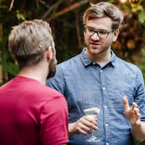 Wie mit Corona-Skeptikern im Umfeld umgehen? Zwei Männer stehen im Garten und unterhalten sich.