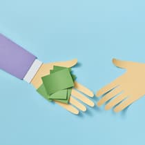 Freunden Geld pumpen: Darauf sollten Sie achten Eine Hand aus Papier gefaltet, überreicht einer zweiten Papierhand ein kleines Bündel mit Post-its, das sinnbildlich für Geld steht - Wer anderen ein Darlehen vermacht, sollte dies vertraglich festhalten, um die Rückzahlung des Privatdarlehens durch den Schuldner zu regeln.