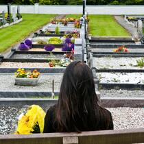 Dank Spenden das Nötigste nach dem Tod des Ehemanns Frau sitzt auf einer Bank auf dem Friedhof