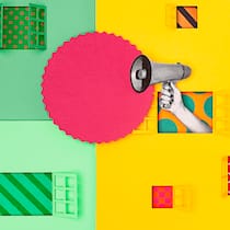 Muss ich laute Nachbarn ertragen? Eine grüne und eine gelbe Hauswand, aus deren Fenster eine Hand mit Megafon herausragt. Wie viel Lärm man unter Nachbarn ertragen muss.