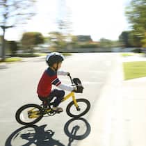 Kinder auf dem Fahrrad Ein kleines Kind fährt mit einem Kindervelo auf einer ruhigen Nebenstrasse.
