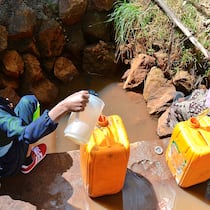 Bundeshilfe für Nestlés Geschäfte Afrikanische Frauen mit Kanistern an Wasserstelle