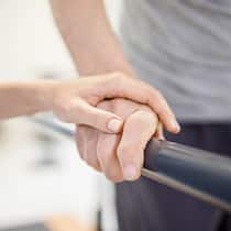 Dank Spenden ein Fitnessabo für einen MS-Kranken Krankenschwester hält Hand von Mann auf Laufband