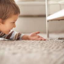 Das Kind betreuen und trotzdem alles bezahlen? Ein kleiner Junge spielt mit einer Katze, die sich unter dem Bett versteckt hat. Bei geschiedenen Eltern, deren Obhut über die Kinder ungleichmässig verteilt ist, stellt sich die Frage, wie sie die Unterhaltskosten für das Kind aufteilen.