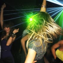 Wenn Teenies ins Nachtleben wollen – was können Eltern tun? Eine Gruppe Frauen tanzt vor grünem Club-Licht. Wenn Jugendliche in den Ausgang wollen, sollten Eltern klare Regeln festlegen.