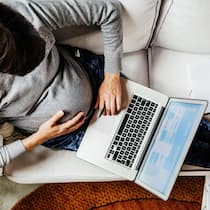 Mutter wehrt sich gegen diskriminierendes Arbeitszeugnis – und scheitert An aerial view of a pregnant woman sitting on her couch using her laptop, working from home during the day.
1180387560
