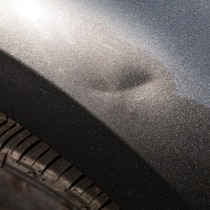 Eine Faust fliegt – aber die Delle im Ferrari bleibt straffrei Minor car dent on car fender. Depreciation concept of dented fender for autobody repair, car maintenance, fender bender, or buying a used car or SUV with minor damage. Car exterior photographed during day, outdoors. Part of a series.