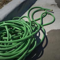 Krieg um Gartenschlauch eskaliert A green water hose lying on the ground. Photographer: Nitashia Johnson/Bloomberg
2149086601