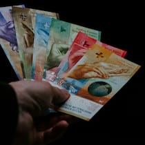 Architekt kauft sich mit Darlehen zwei Boliden – und wandert ins Gefängnis Eine Hand hält einen Geldfächer mit Schweizer Banknoten vor schwarzem Hintergrund.Symbolbild, Betrug, Korruption